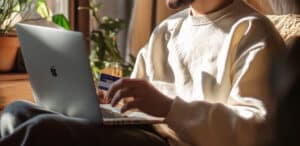 a man holding a credit card and using a laptop on his lap