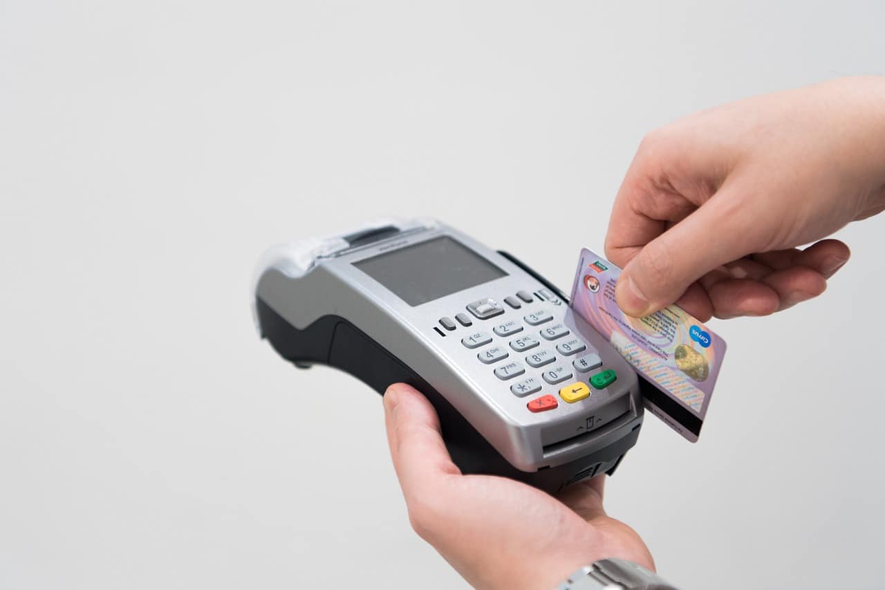 A person running a debit or credit card through a payment processor machine