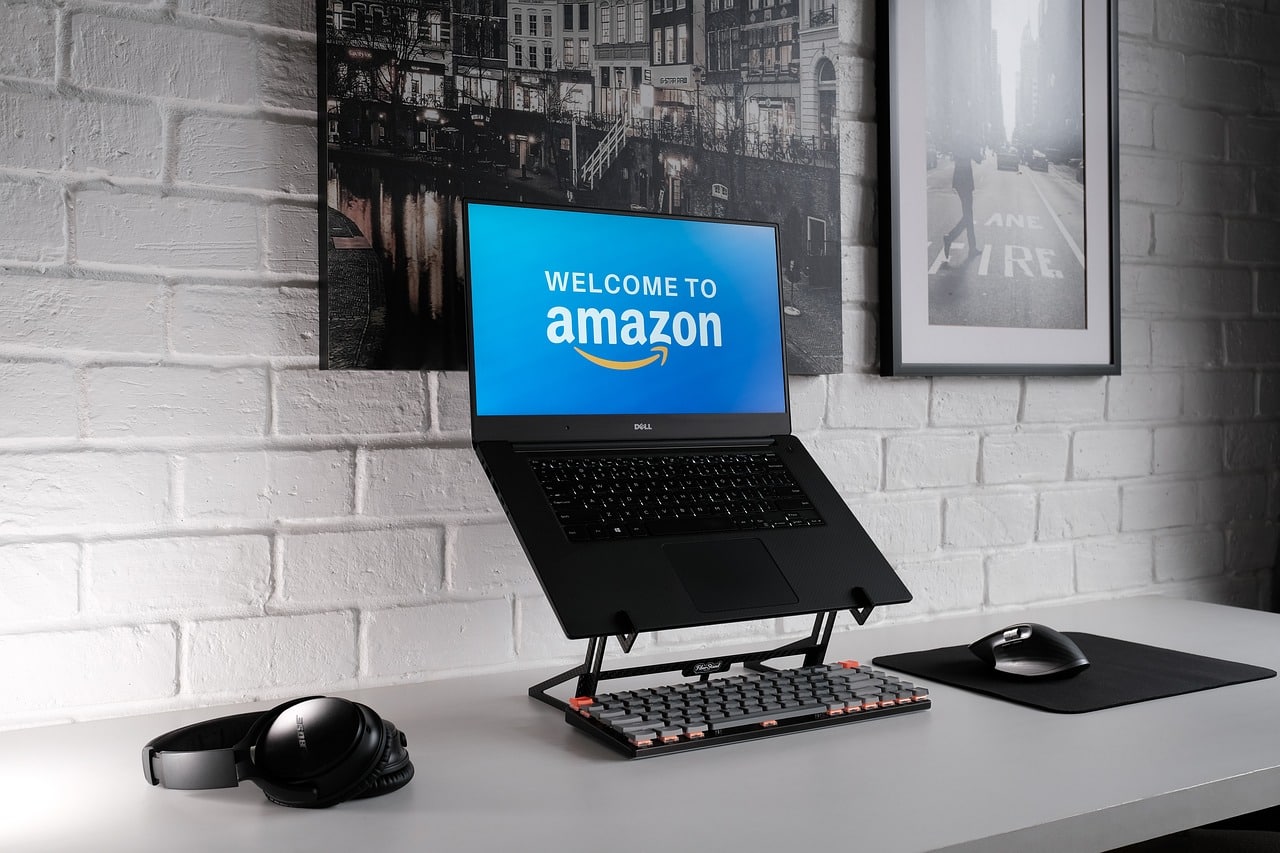 A laptop propped up on a desk with a screen reading "Welcome to Amazon"