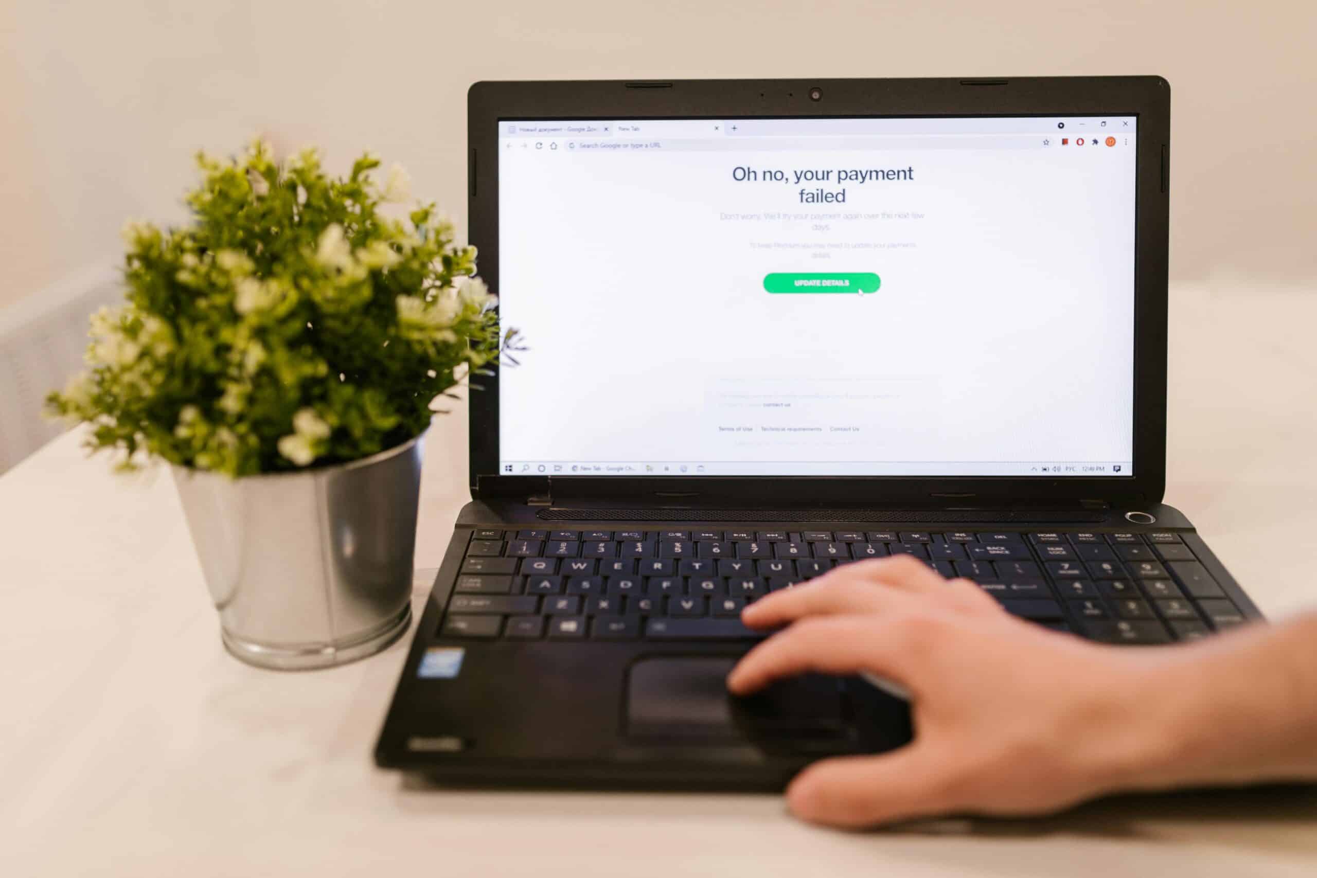 Payment error declined message while hand uses laptop with plant nearby