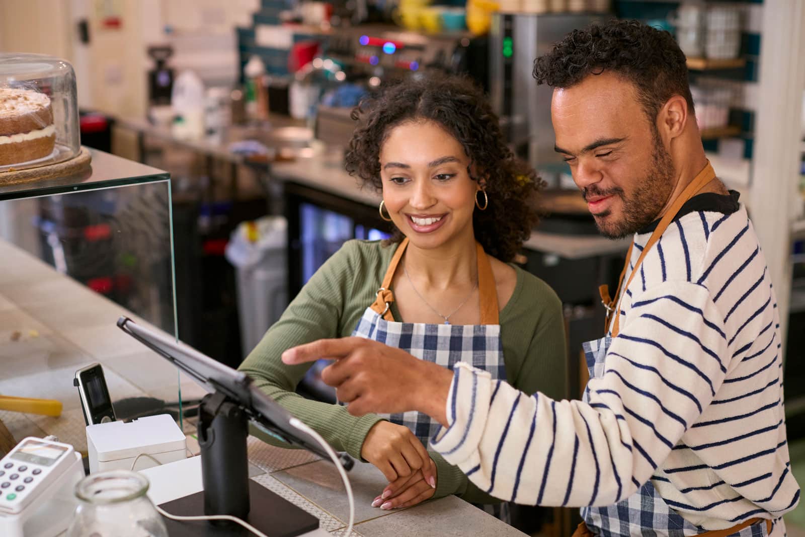 credit card processing fees comparison for restaurants; Man and woman pointing and smiling at computer in a store setting