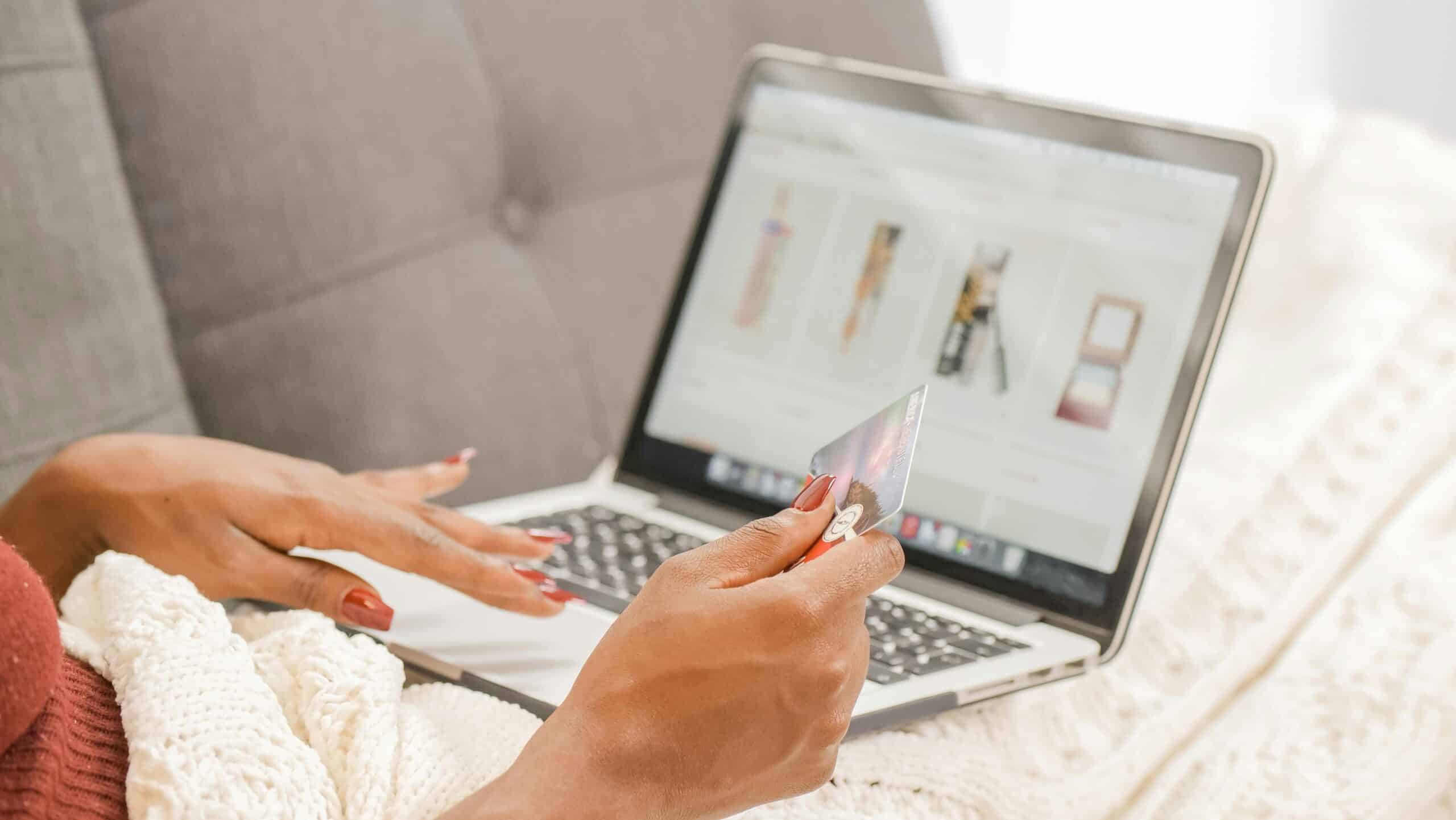 Person holding credit card in front of laptop