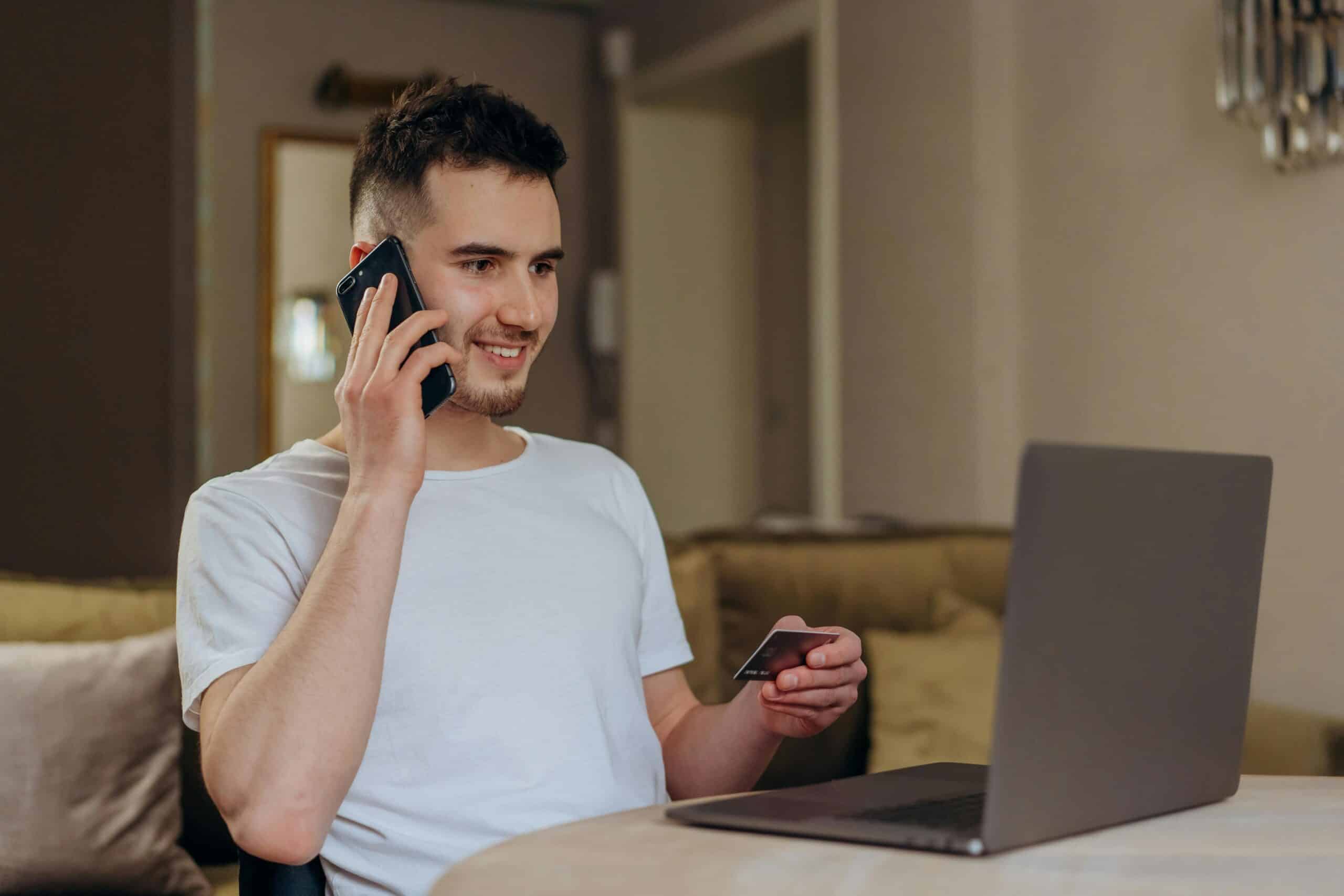 Man talking on the phone and using credit card with laptop