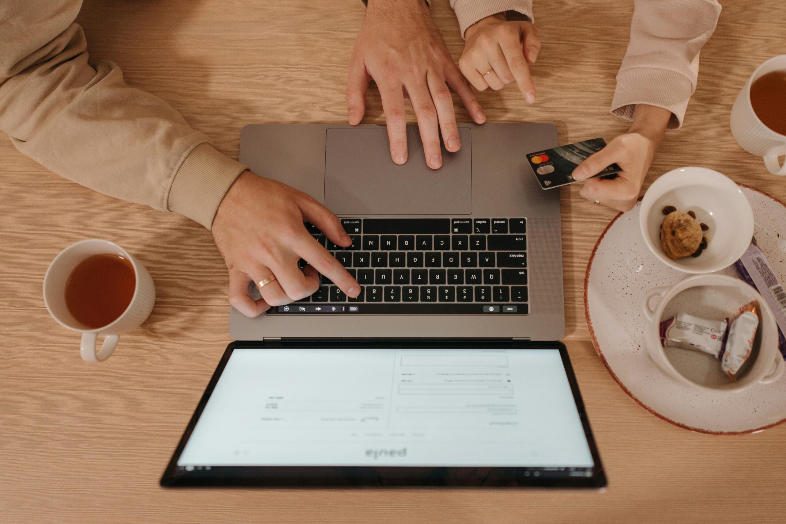 Pair of people using credit card with computer.