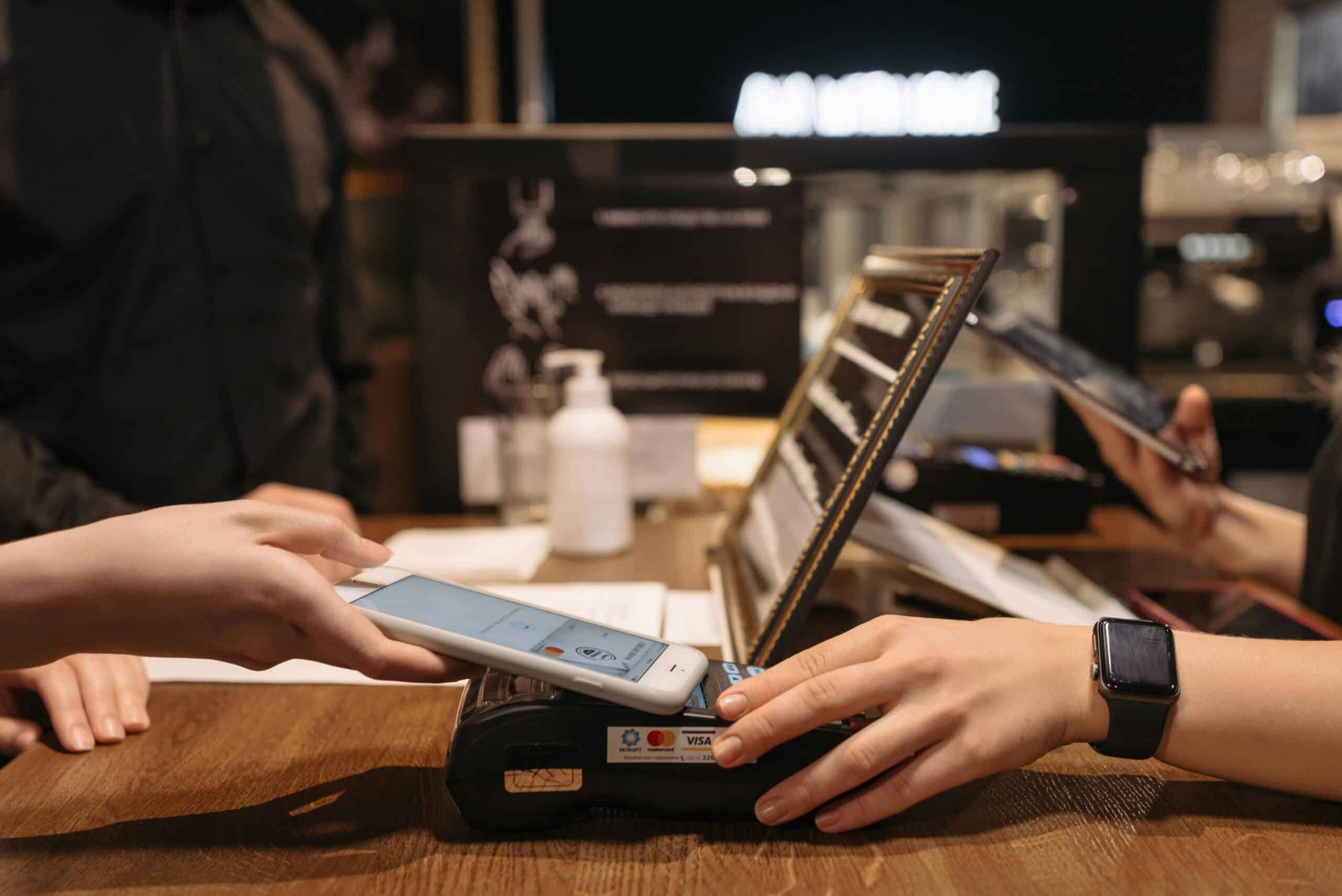 A person using a phone to complete a mobile touchless checkout at a POS device