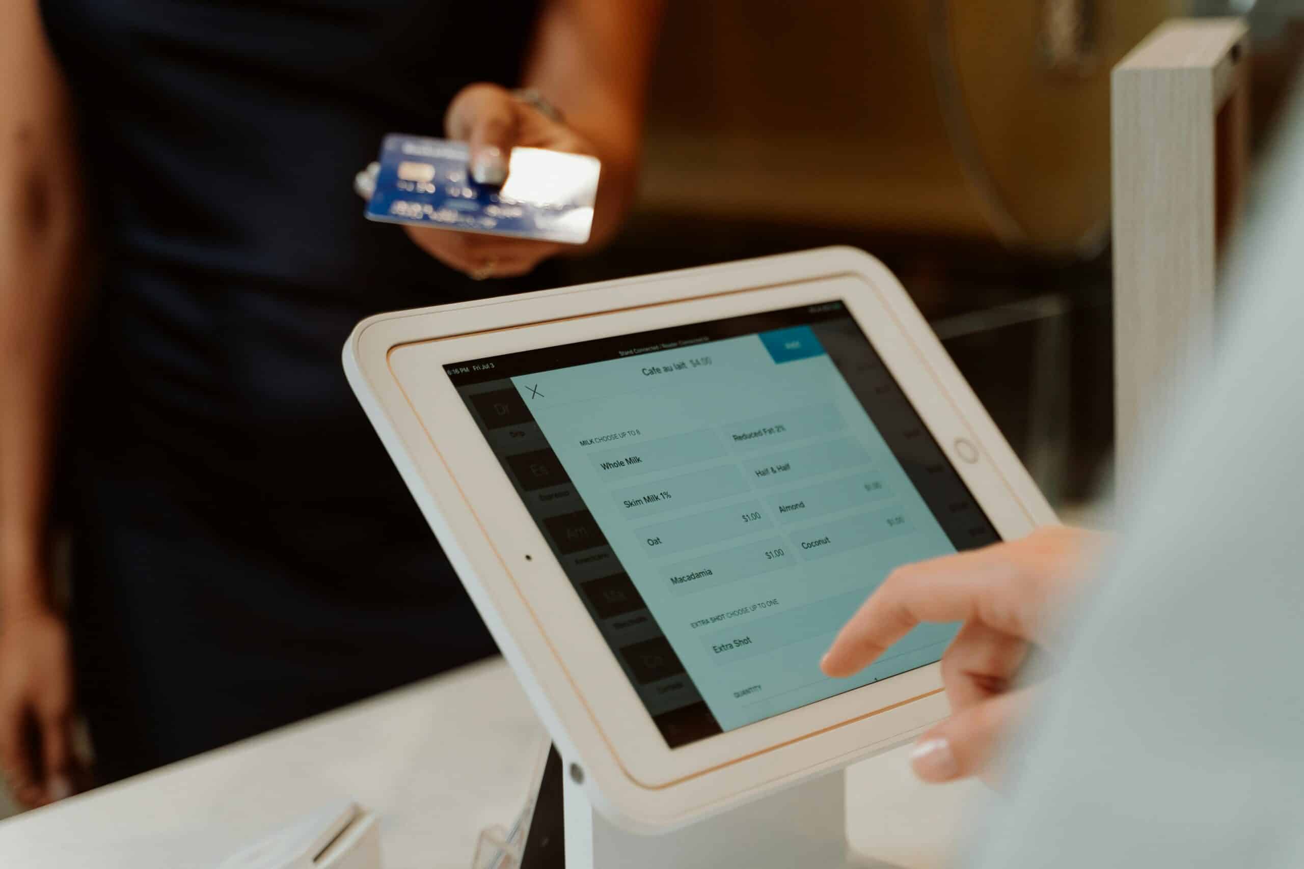 A person holding a credit card to a POS system for checkout