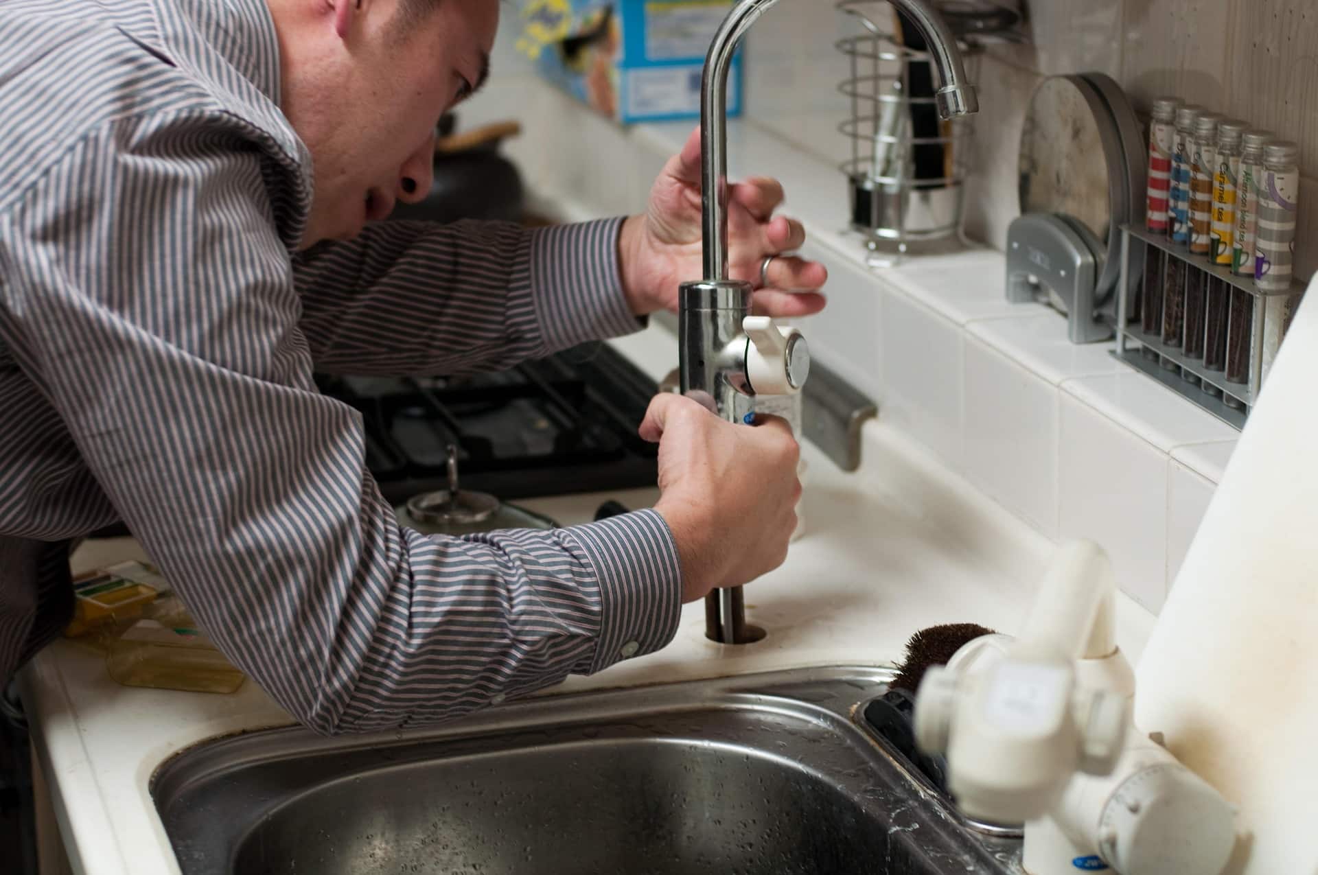 plumber working on sink and accepting mobile payment processing for home contract work